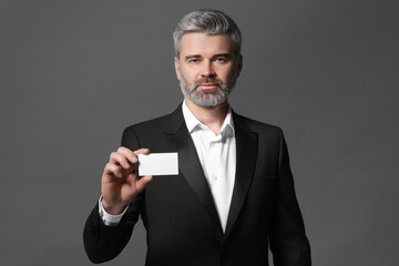 Canvas Print - Handsome businessman holding blank business card on grey background