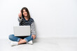 © luismolinero - Young caucasian woman with a laptop sitting on the floor isolated on white background showing and lifting a finger