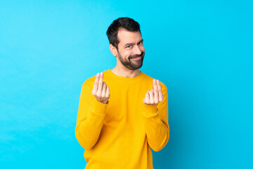 Sticker - Young caucasian man over isolated blue background making money gesture