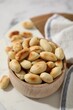 Roasted peanuts in bowl on white table, closeup