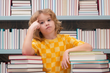 Aufkleber - Thinking school kid. Schoolboy pupil reading book at school. Kid doing homework, sitting at table by books, in library.