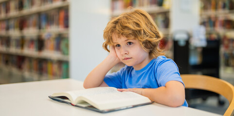 Aufkleber - Kid reading book. Child reading book in a public library. Education and school concept. Little student studying and reading book at school library.