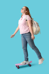 Wall Mural - Happy female student with backpack and skateboard on blue background