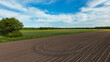 © TravelLensPro - Dirt road cuts through grassy field under blue sky 4K FPV drone view Hanover Seelze Germany