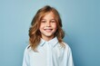 © MediaRaw - A young girl with long brown hair is smiling and wearing a blue shirt