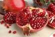 Piece of fresh pomegranate and seeds on white table, closeup