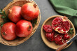 Fresh pomegranates, green leaves and knife on grey table, top view