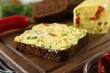 Tasty butter with green onion, chili pepper and rye bread on table, closeup