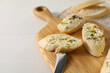 Tasty butter with olives, green onion, bread and knife on white table, closeup. Space for text