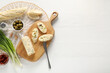 Tasty butter, bread and other ingredients on white wooden table, top view. Space for text