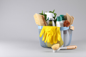 Poster - Set of different cleaning supplies in basket on light grey background. Space for text