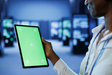 Poster - experienced developer in server room uses green screen tablet to future proof network from downtimes