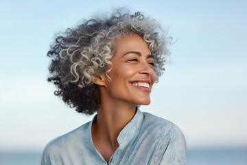 A woman with a short, curly, gray hair is smiling and looking at the camera