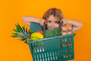 Wall Mural - Food store. Little child shopping with shopping basket. Sales and shopping. Kid with shopping basket purchasing food in a grocery store. Little customers buying products at supermarket.