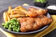Tasty fish, chips and peas on table, closeup