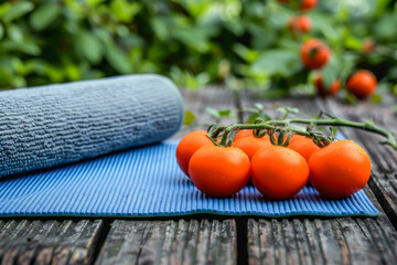 Wall Mural - a blue yoga mat is on a wooden table with a bunch of red tomatoes on top of it