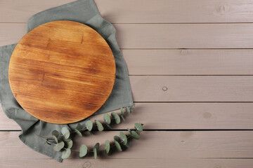 Wall Mural - Cutting board, eucalyptus branches and napkin on beige wooden table, top view. Space for text