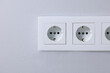 Electric power sockets on light grey wall indoors, closeup