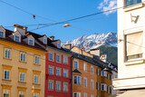 Fototapeta Uliczki - The snow capped Austrian Alps can be seen above the colorful medieval buildings in the historic old town center of Innsbruck, Austria.