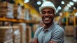 © Saowanee - Young professional African American man wearing a grey polo shirt and white hard hat. He seems to be happily working. in the packaging factory Wearing a white helmet indicates safety.