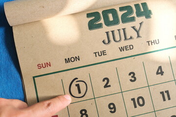 Wall Mural - Hand pointing on July 1 2024 date on calendar flat lay in blue background. Canada day celebration reminder.	