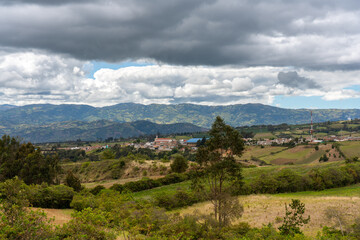 Wall Mural - Church in a town seen in the distance surrounded by country landscape with mountains in Colombia.