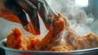 Close-up of a hand reaching into a bucket of fried chicken, steam rising as it grasps a delectable piece