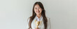 an Asian teenager clad in a pristine white suit and shirt proudly holds a gold trophy, symbolizing her dedication to academic success, against a white backdrop.