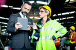 © Stella - Beautiful woman industrial engineer worker wearing safely helmet and protective clothing, holding tablet and discussing with her senior businessman manager, at heavy industry manufacturing factory