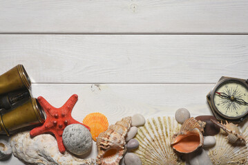 Wall Mural - Vintage compass, binoculars, seashells and pebble stones on the white wooden desk table close up background with copy space.