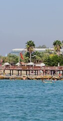 Wall Mural - Portrait footage of the beautiful beach in Antalya, Turkey showing people relaxing and having fun on the beach in the summer time.