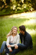 Couple, embrace and outdoor love on grass, together and care in relationship or bonding in park. Happy people, support and hug on holiday or vacation in nature, relax and commitment on romance date