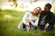 © peopleimages.com - Couple, embrace and relax outdoors on grass, together and love in relationship or bonding in park. Happy people, support and hug on holiday or vacation in nature, laughing and commitment on date