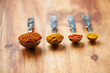 Spoons, spice and collection of powder for seasoning on kitchen table, turmeric and paprika for meal. Digestion, condiments and options for cooking in Indian culture, weight loss and food preparation