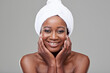 © peopleimages.com - African woman, skin or towel with face in studio for beauty, makeup or cosmetics with happiness. Female model, smile or aesthetics with confidence on backdrop in portrait, skincare in Nigeria