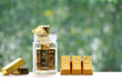 Saving gold, Woman hand putting gold bar in the glass bottle on natural green background,Business investment and Saving money for prepare in future