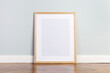Blank picture frame template on floor. Mint color wall and stylish parquet floor