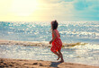 Happy little girl runs on the beach in summer