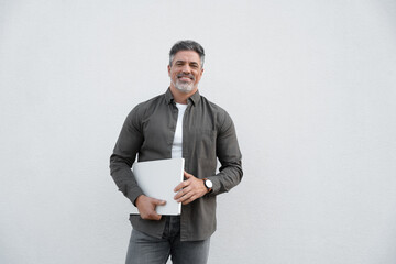 Happy portrait successful latin hispanic businessman holding wireless pc laptop computer for business. Mature smiling middle age man freelance entrepreneur looking at camera Isolated, white background