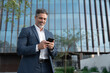© Stock 4 You - Smiling mature hispanic senior business man using smartphone cellphone at office building. Latin middle age male entrepreneur businessman holding mobile cell phone for trading outdoors. Copy space