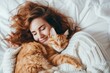 Young woman tenderly hugs her cat tightly lying in a light bed. Friendship concept between humans and animals