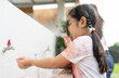 Little girl washing hands with soap at an outdoor faucet after activity outdoor painting watercolor at school. Kids hygiene and health concept.