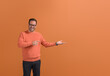 © Moon Safari - Portrait of smiling male promoter showing empty palm and marketing new product on orange background