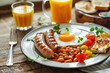 tasty healthy breakfast, fried egg , sausage, baked beans, and tomatoes on plate, glass of orange juice on wooden table on kitchen 