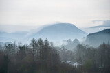 Fototapeta Londyn - Stunning layered landscape image of misty Spring morning in Lake District looking towards distant misty peaks