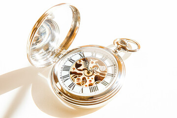 A classic pocket watch with a silver case and Roman numerals on the face, lying open on a clean white background. 