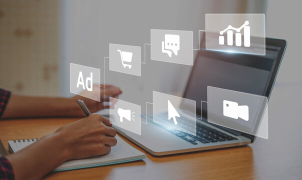 Digital marketing concept with businessman using computer laptop creating online adverts to increase sales. Using social media and websites for traffic and awareness, working in a modern office.