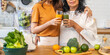 Young woman and elderly mother in healthy lifestyle, glass with nutritious beverages, daughter hold orange juice, vitamins, mother enjoys a green vegetable smoothie, health, family, care, healthy diet