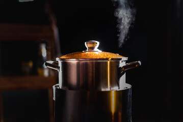 Wall Mural - A boiling pot shoots up steam as a chef cooks food in a restaurant.