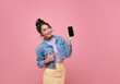 Beautiful Asian woman showing and pointing finger to smartphone mockup of blank screen isolated on pink background.